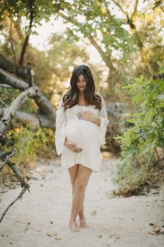 a pregnant woman is standing in the woods with her belly wrapped around her waist and holding her hand on her stomach