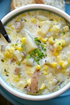 a bowl of corn and potato chowee on a blue plate with a slice of bread