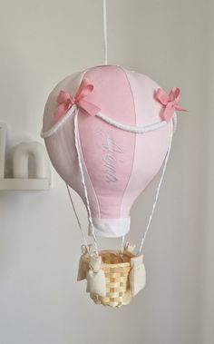 a pink and white hot air balloon hanging from a string on a wall next to a shelf