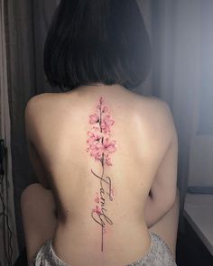 a woman's back with pink flowers and the word faith written in cursive writing