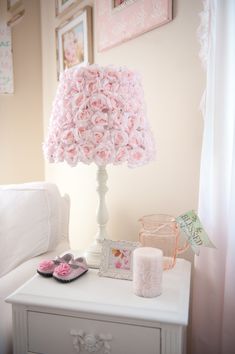 a white table with pink flowers on it and a pair of slippers next to the lamp