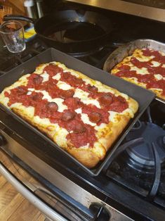 two square pizzas sitting on top of an oven