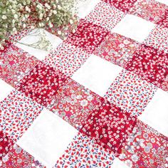 a red and white patchwork quilt with flowers in the center on top of it