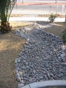 there is a stone path in the middle of some rocks and gravel next to a fire hydrant