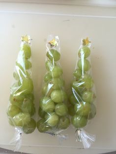 three bags filled with green grapes sitting on top of a white counter next to each other