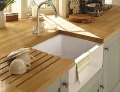 a kitchen counter with a sink and wooden cutting board