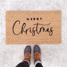 someone standing in front of a merry christmas door mat