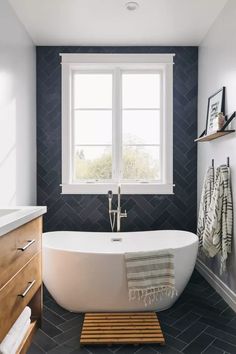 a white bath tub sitting under a window next to a wooden cabinet and counter top