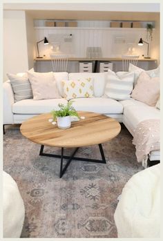 a living room with white couches and pillows on the floor in front of a coffee table