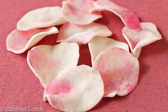 some pink and white flowers on a red table cloth with the petals wilting off