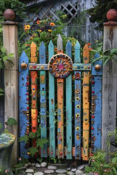 a colorful wooden gate is surrounded by flowers and greenery in the garden, as well as a bench