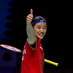 a woman holding a tennis racquet giving the thumbs up