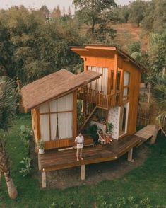 a person standing on a wooden deck in front of a small house with a thatched roof