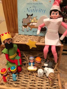 two elf dolls sitting on top of a wicker shelf filled with toys and books