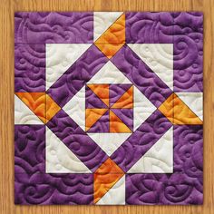 an orange and purple quilted piece on top of a wooden table