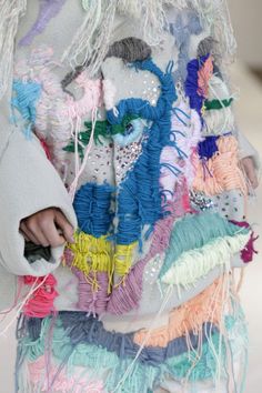 a close up of a person's hand on a colorful piece of clothing that is covered in beads