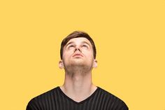 a man looking up with his eyes closed in front of an orange and yellow background