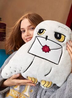 a girl is holding an owl pillow in her arms