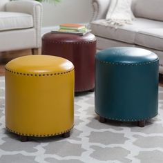 three different colored stools sitting on top of a rug