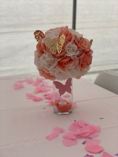 a vase filled with pink flowers on top of a table covered in confetti