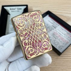 a gold colored lighter sitting on top of a wooden table next to a black box