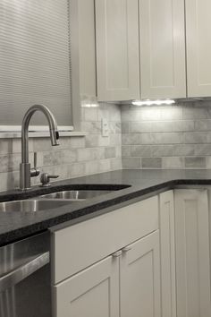 a kitchen with white cabinets and marble counter tops, stainless steel dishwasher and sink