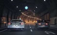 two cars driving down a tunnel at night