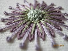 a close up of a flower on a white table cloth with purple and green accents