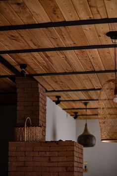 some lights hanging from the ceiling in a room with brick walls and wood beams on the ceiling