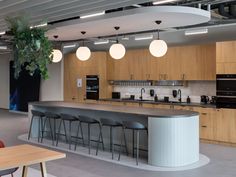 an open kitchen with lots of counter space and hanging lights above the island, along with bar stools