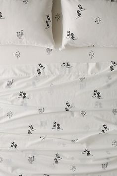 an unmade bed with white sheets and black and white animal print on it, along with two pillows