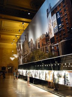 people are standing in front of a large wall with pictures on it and lights hanging from the ceiling