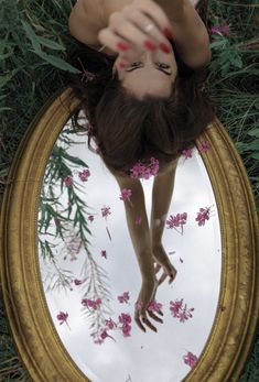 a woman laying on the ground in front of a mirror with flowers all over it