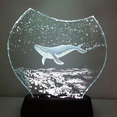 a glass vase with a whale in the water inside it on top of a table