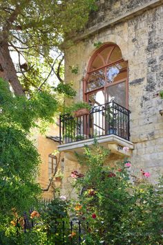 an old building with lots of flowers and trees