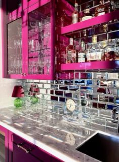 a kitchen with pink cabinets and shelves filled with liquor bottles on top of the counter