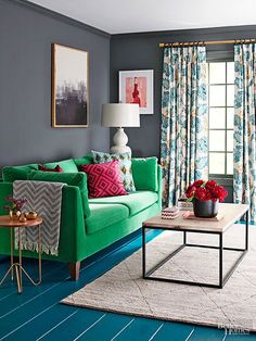 a living room filled with green couches and colorful pillows next to a window covered in curtains