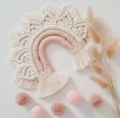 the crocheted hat is next to some pink pom - poms and a plant