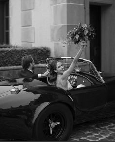 black and white photograph of a woman in a convertible car with her arm up to the man's head