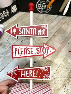 a hand holding a red and white street sign on top of a wooden table next to other signs