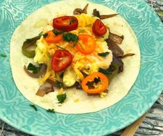 a tortilla topped with eggs, peppers and onions on top of a blue plate