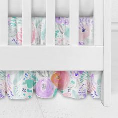 a white crib bed with colorful flowers on it