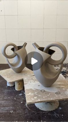 two gray vases sitting on top of a table