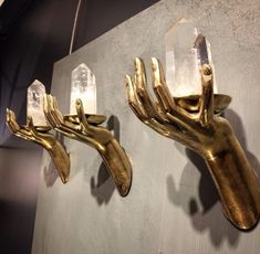 two gold wall sconces with crystal hands hanging on the wall next to each other