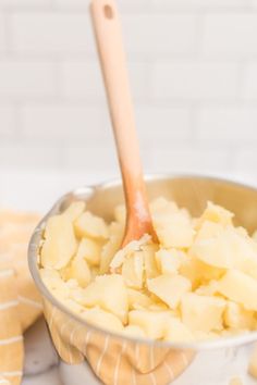 a wooden spoon in a bowl filled with potatoes