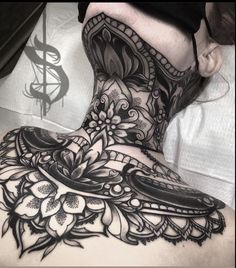 the back of a woman's neck is covered in black and white tattoos with flowers