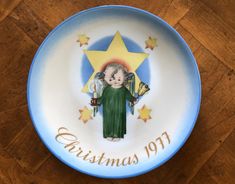 a blue and white plate with an angel holding a star on it's side