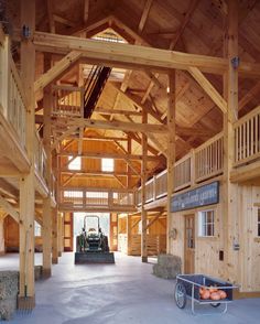 the inside of a barn with hay bales and a cart full of oranges