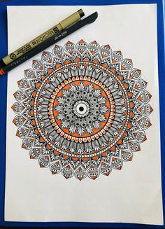 an orange and white coloring book with a black marker on it next to a pen