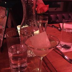 a table topped with glasses filled with water and ice next to a vase full of flowers